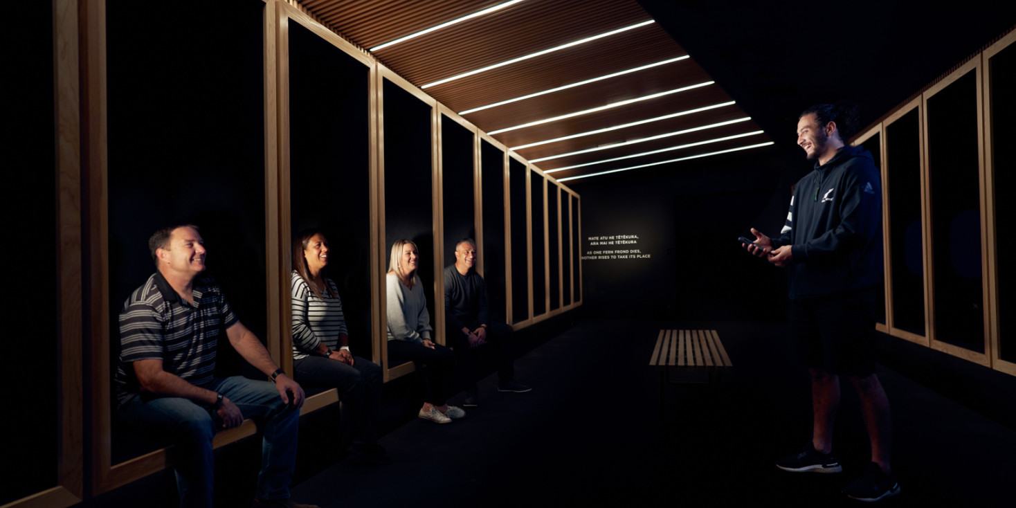 Group sitting in dark rugby changing room listening to a person speaking