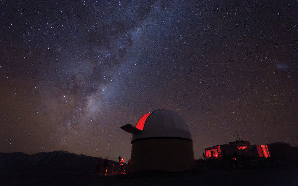 View of milky way with observatory in foreground at top of Mt John