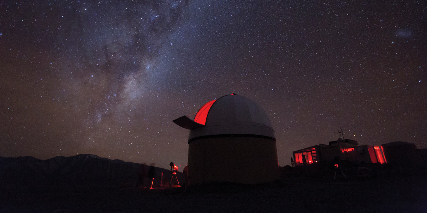 View of milky way with observatory in foreground at top of Mt John