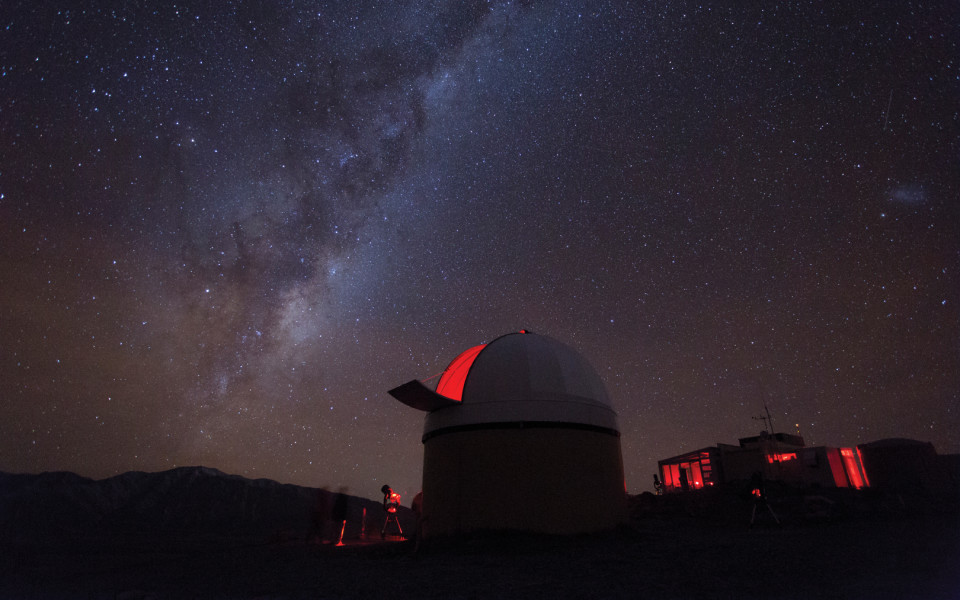 View of milky way with observatory in foreground at top of Mt John