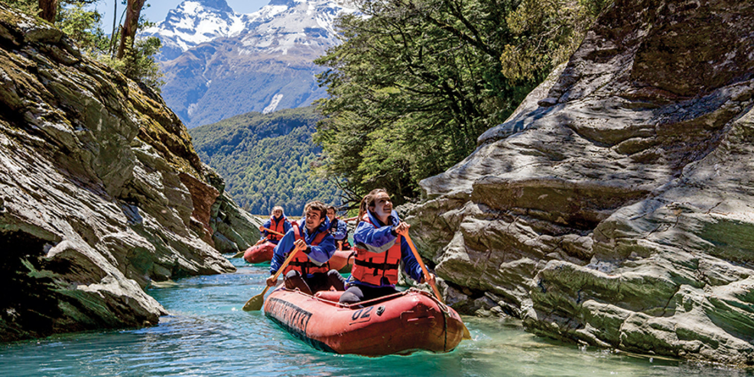 Group of inflatable canoes paddling through rocky channel 