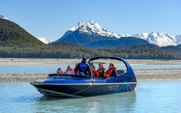 Dart River Jet Boat full of tourists against Richardson Mountain range backdrop