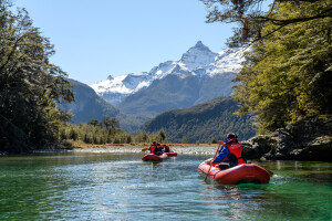 Pair of inflatable canoes paddling towards a snowcapped mountain 