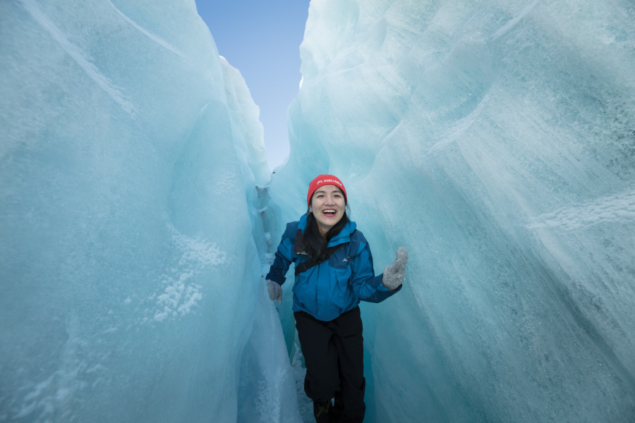 Woman smiling in between an ice crevice on the Glacier