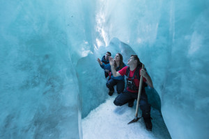 Group huddling together underneath large block of ice on glacier