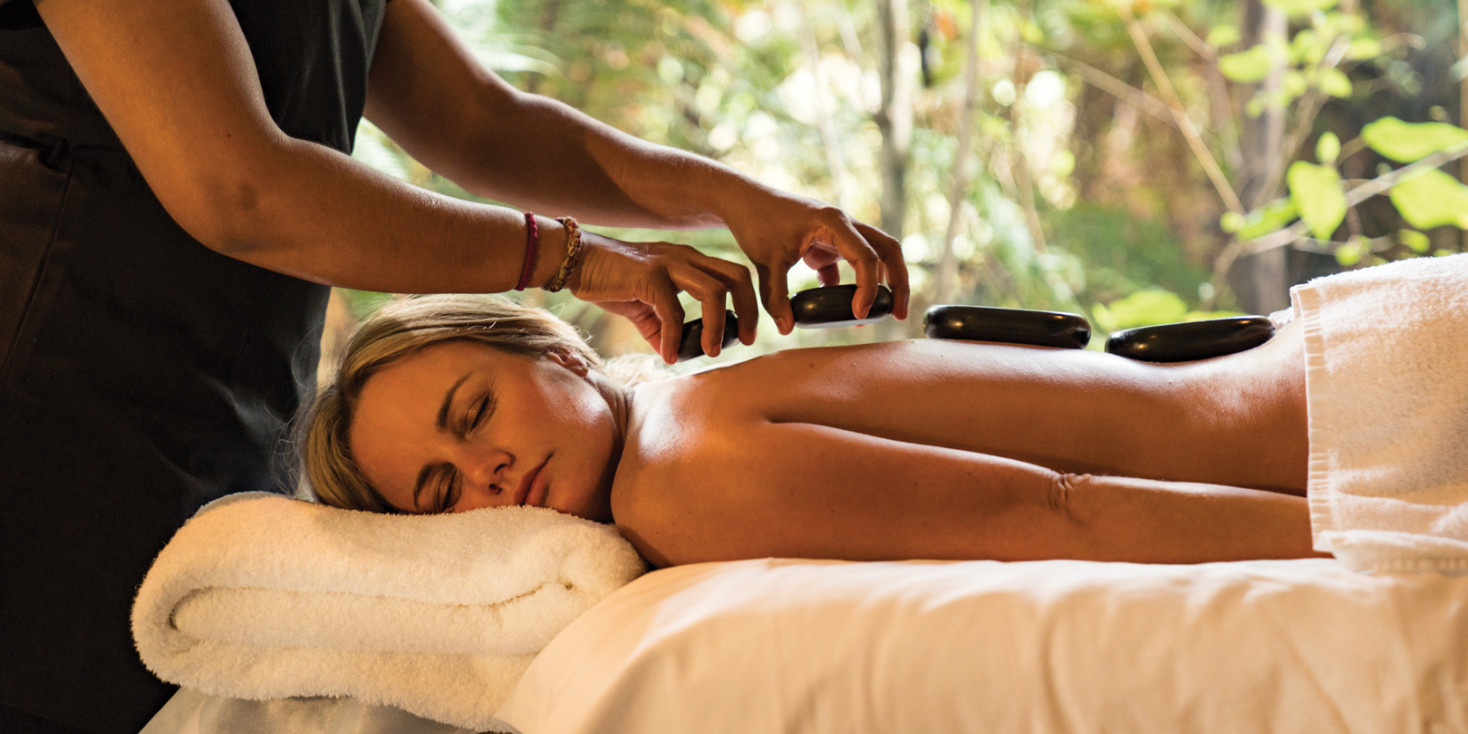 Woman lying down on massage table with hot rocks on her back