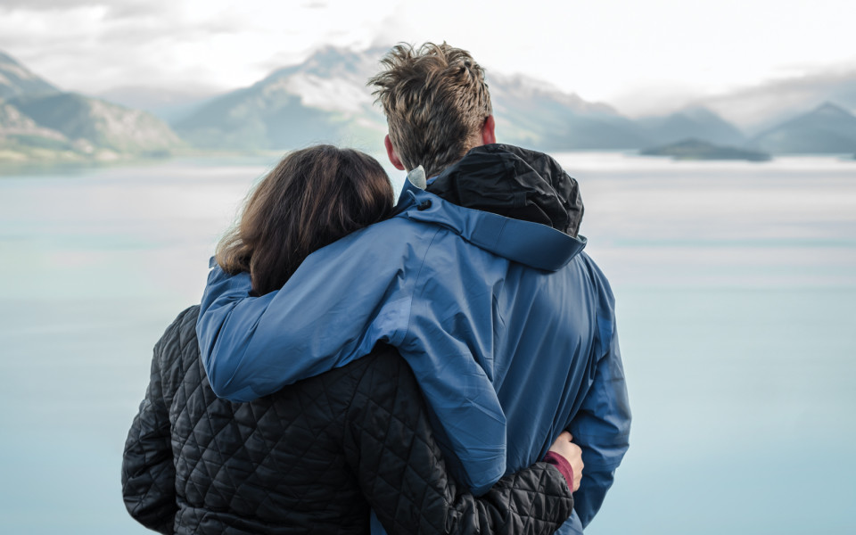 Couple embracing overlooking alpine river