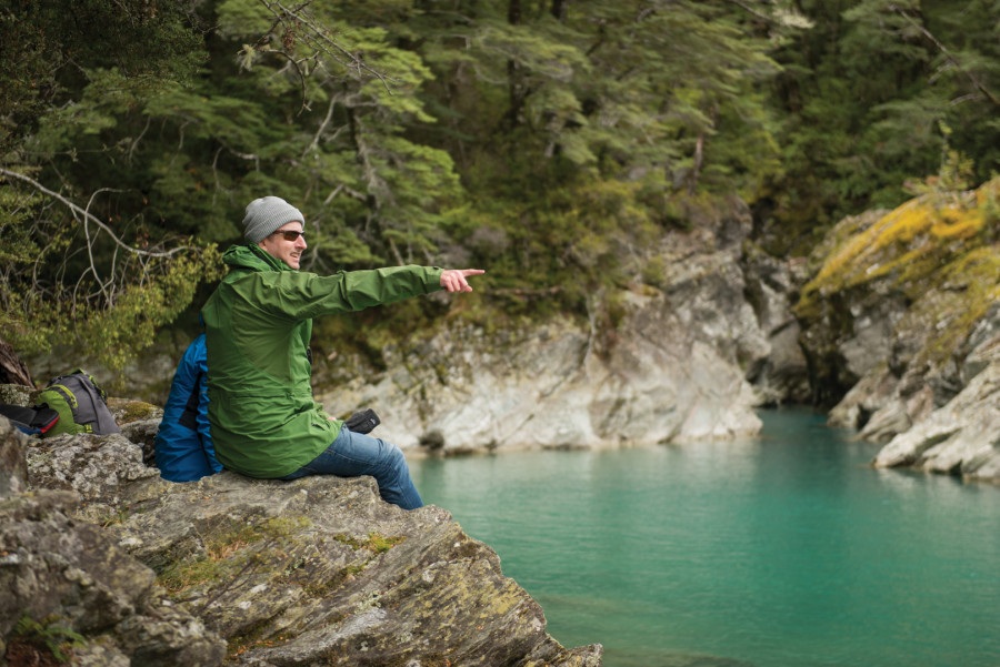 Man sitting on rocks pointing across river