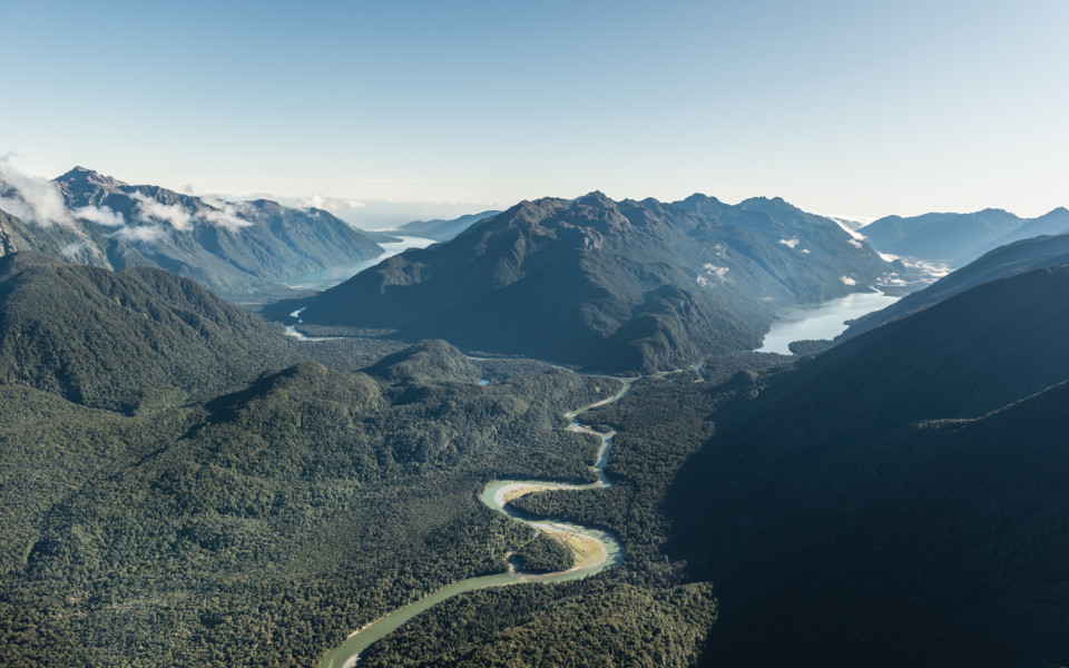 Winding river through native forest between mountain range