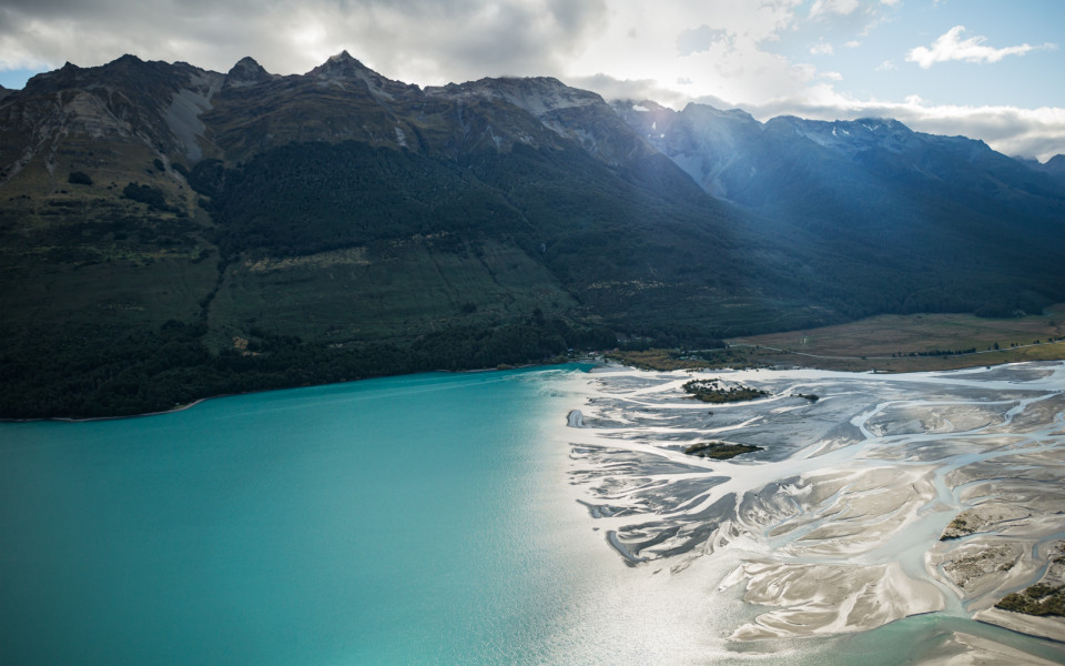 Mountain range and braided river meeting the lake waters