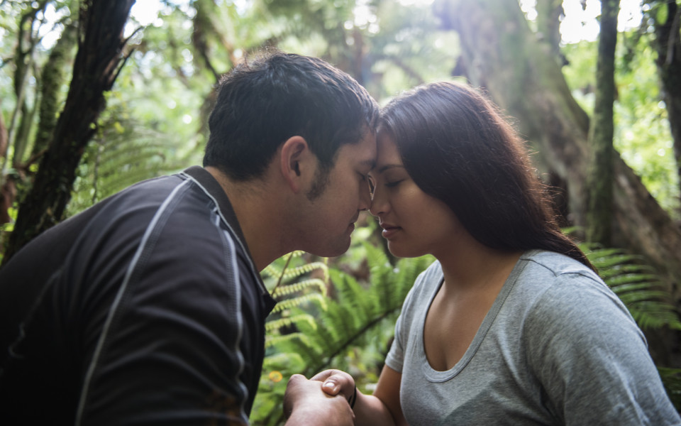 Man and woman presses noses in traditional maori hongi