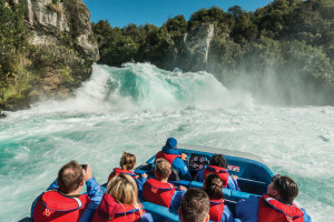 Passengers on jet boat admiring powerful waterfall 