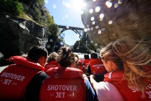 Shot of passengers from behind on shotover jet travelling toward bridge