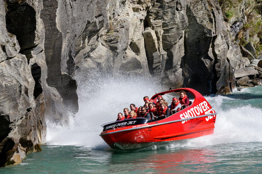 Jet boat speeds along river towards rocky cliff face