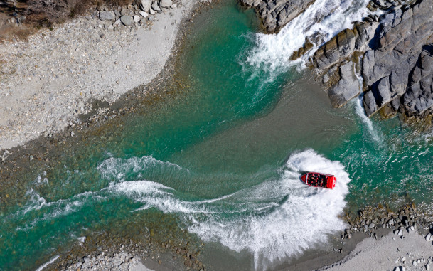 Aerial view of shotover jet doing a spin in shallow river