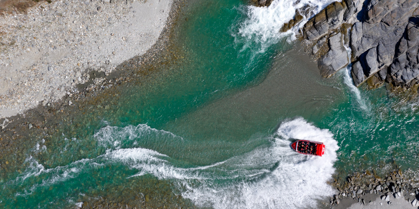 Aerial view of shotover jet doing a spin in shallow river